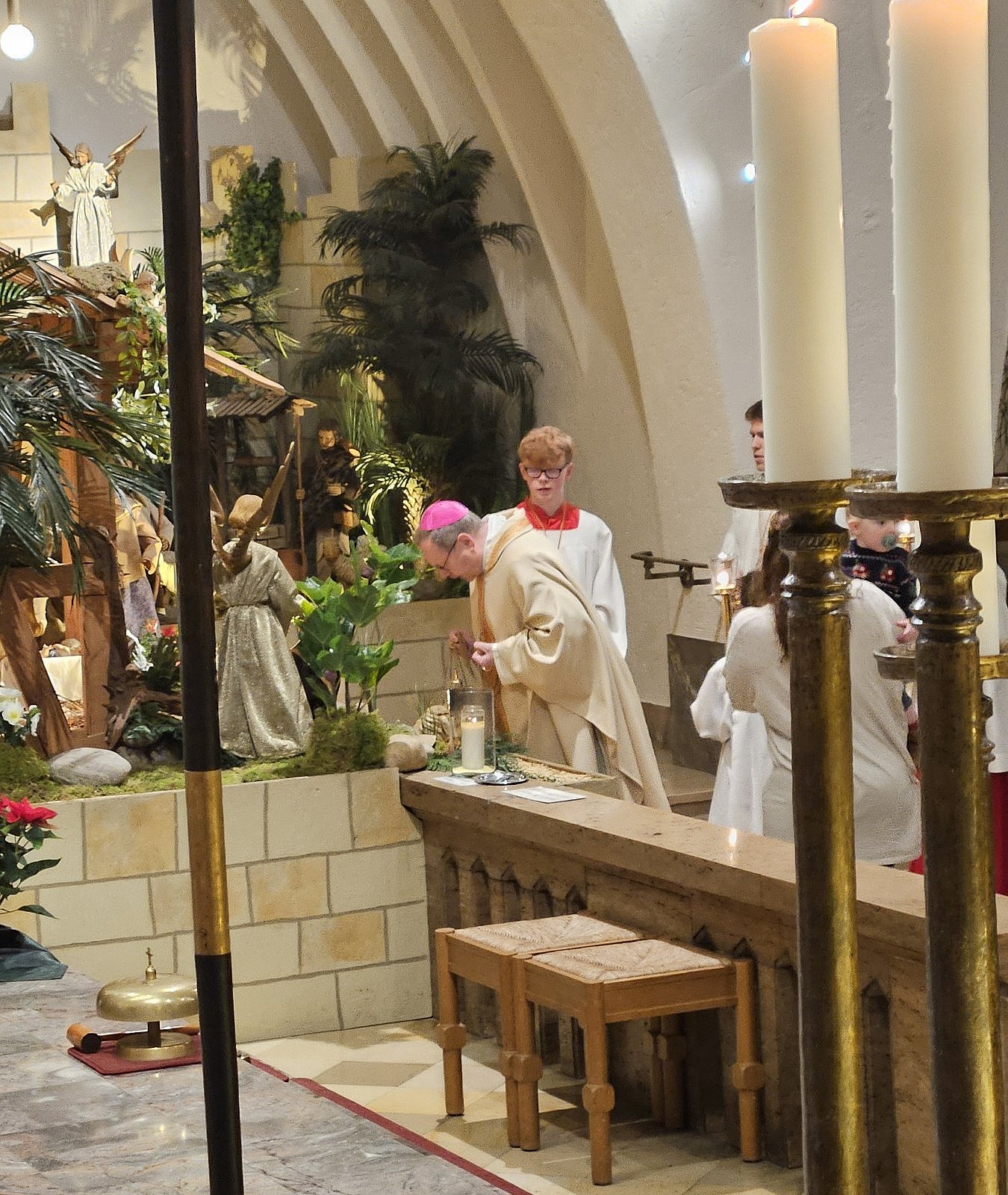 Bischof Georg verbeugt sich vor dem Jesuskind an der Krippe.
