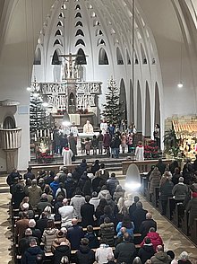 Blick von der Empore zum Altar, an dem Bischof Georg mit den Messdienern und Kindern aus der Gemeinde steht. Die Kirchenbänke sind mit Gläubigen gefüllt.