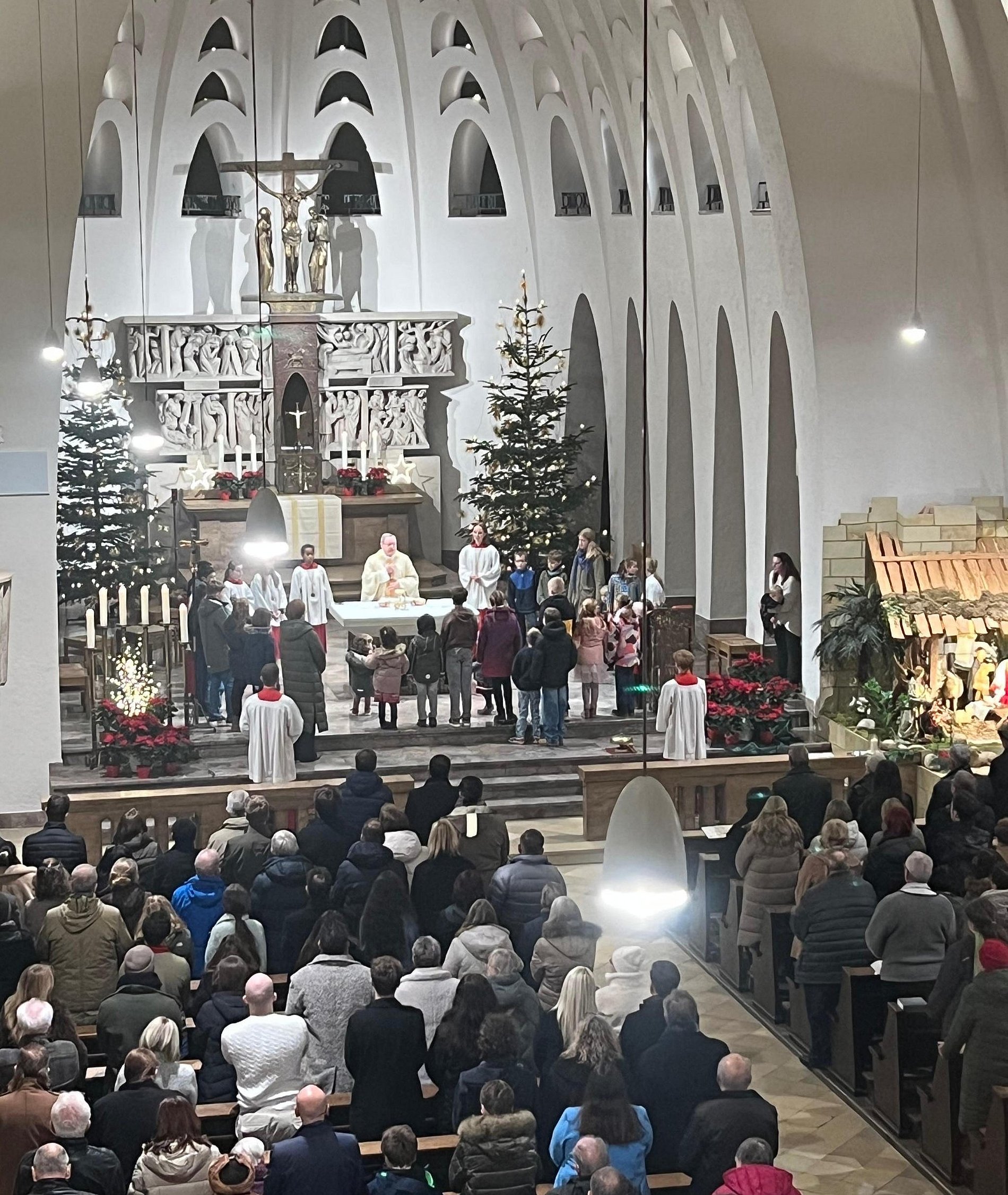 Blick von der Empore zum Altar, an dem Bischof Georg mit den Messdienern und Kindern aus der Gemeinde steht. Die Kirchenbänke sind mit Gläubigen gefüllt.