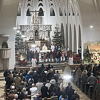 Blick von der Empore zum Altar, an dem Bischof Georg mit den Messdienern und Kindern aus der Gemeinde steht. Die Kirchenbänke sind mit Gläubigen gefüllt.