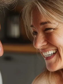 Paar mittleren Alters sitzt in der Küche und lacht zusammen