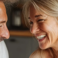 Paar mittleren Alters sitzt in der Küche und lacht zusammen