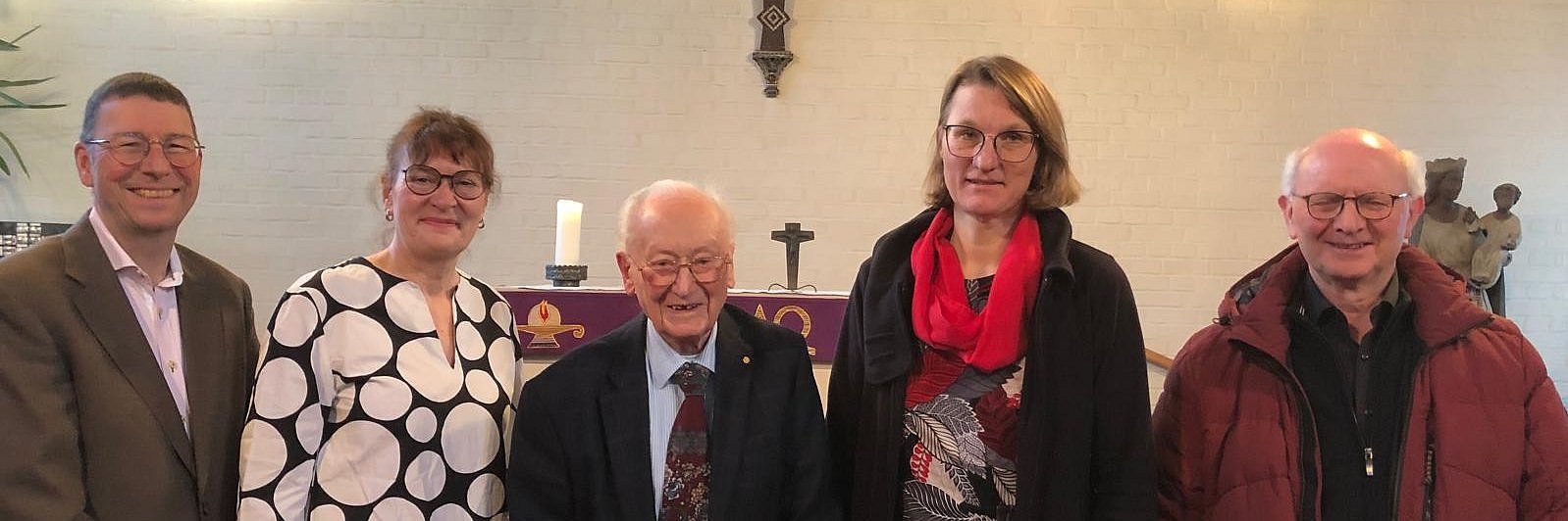 5 Personen stehen nebeneinander vor dem Altar