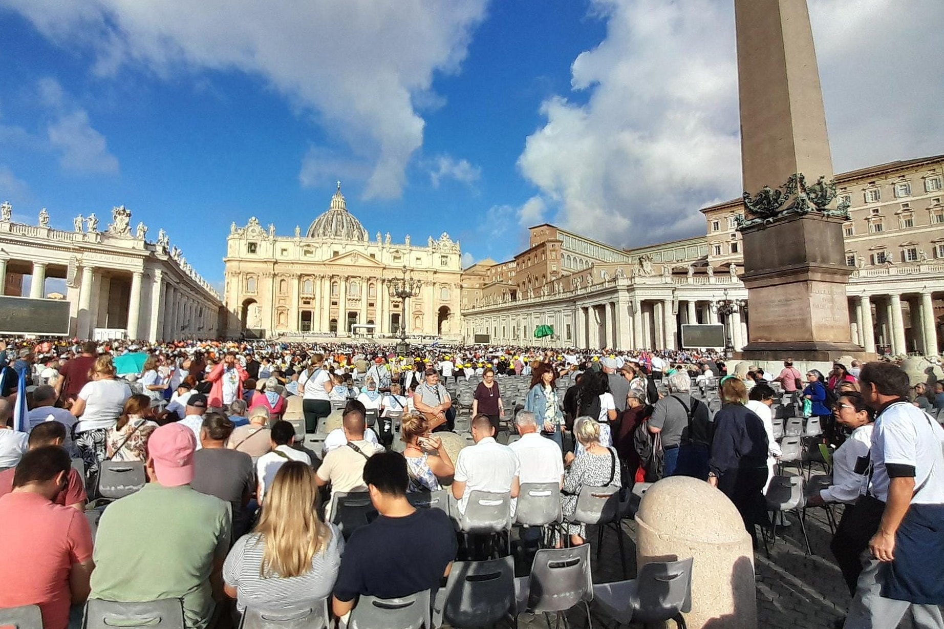 Gläubige sitzen auf dem Petersplatz und warten auf die Papstaudienz