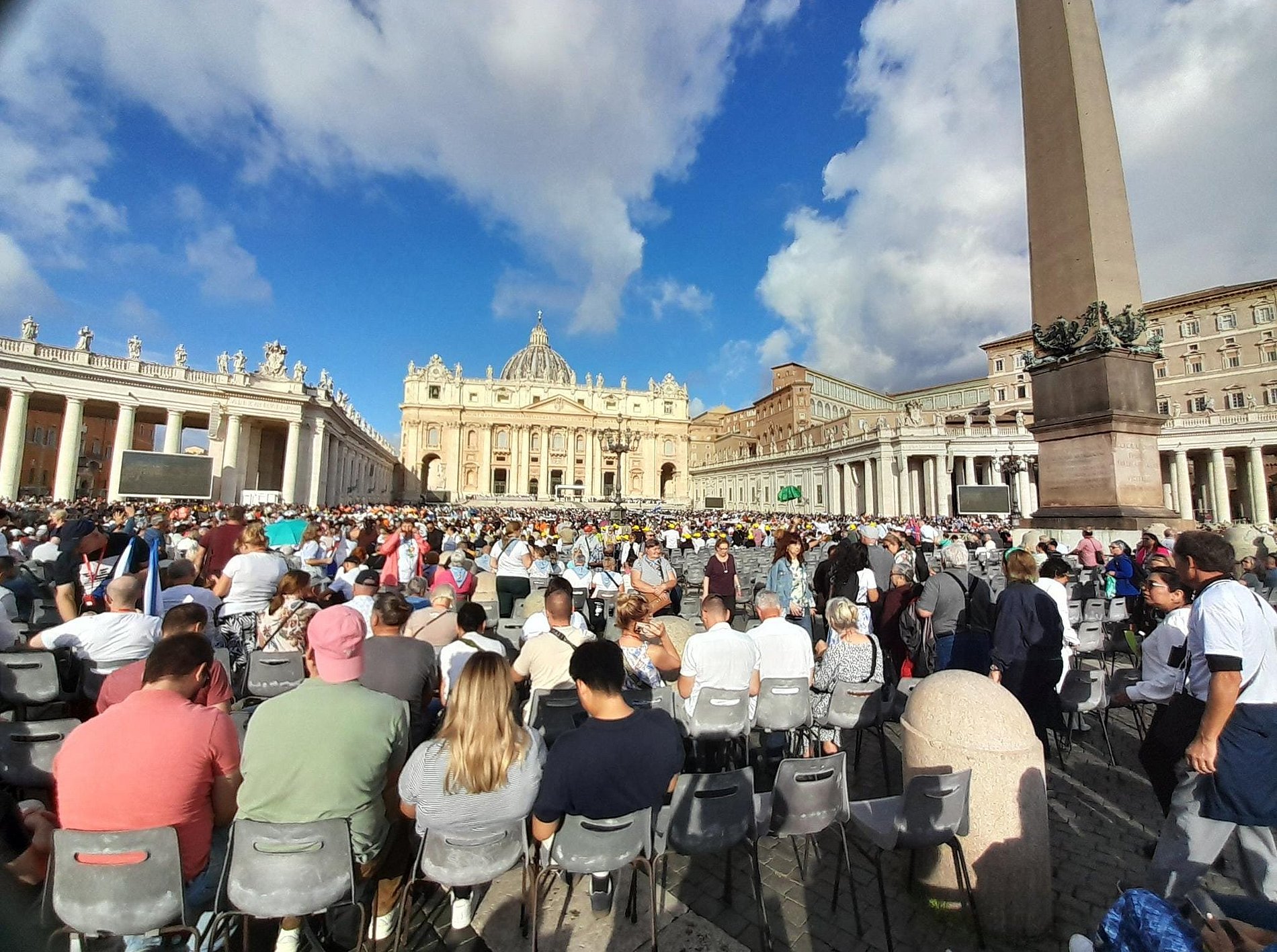 Gläubige sitzen auf dem Petersplatz und warten auf die Papstaudienz