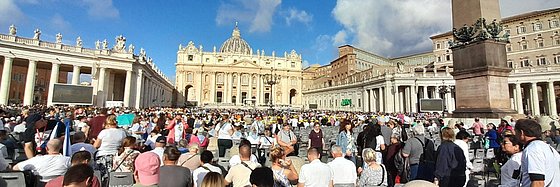Gläubige sitzen auf dem Petersplatz und warten auf die Papstaudienz