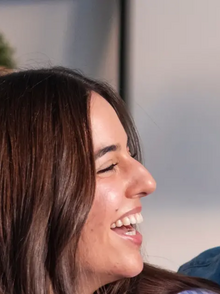 Junges Paar: der Mann lächelt in die Kamera, die Frau zu ihm.