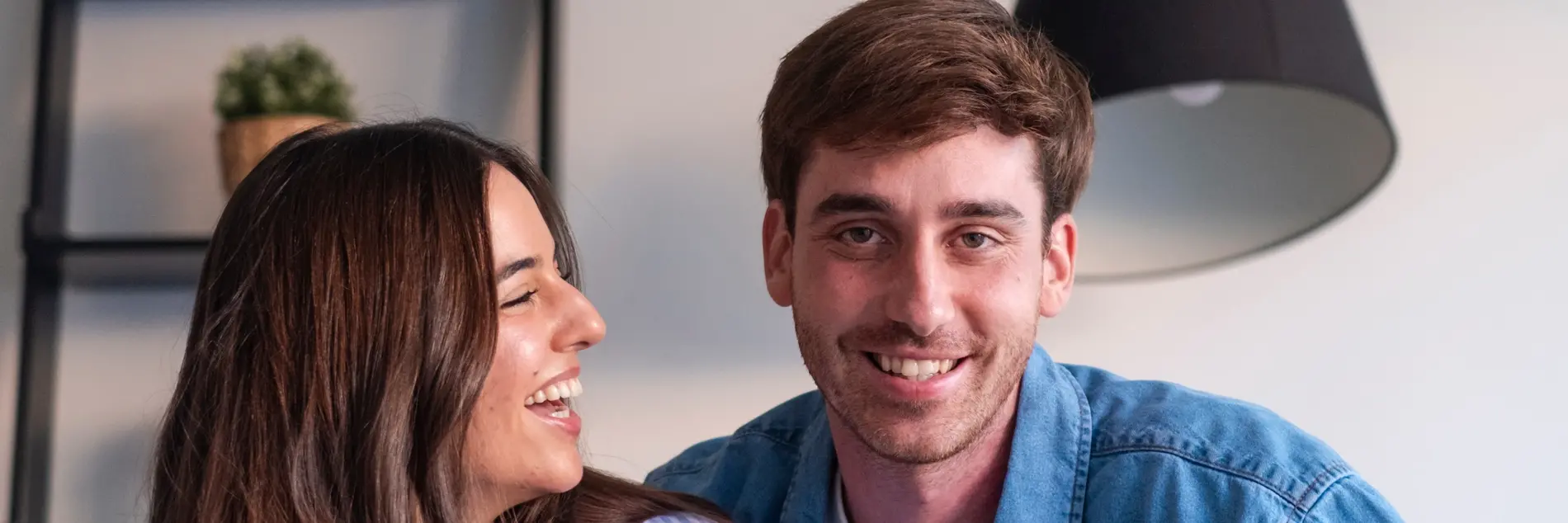Junges Paar: der Mann lächelt in die Kamera, die Frau zu ihm.
